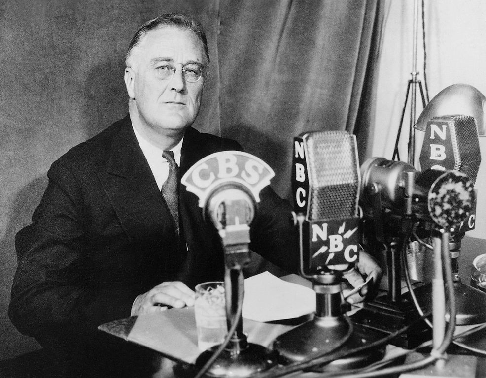 US President Franklin Roosevelt sitting in front of a number of microhpnes