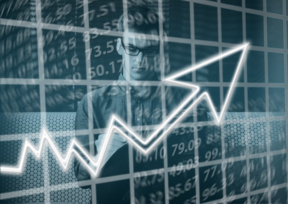 A person writing on paper with graphics of numbers and charts overlaid on top