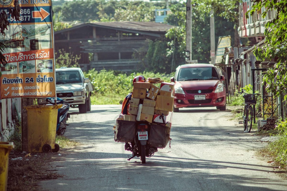 motorcycle carrying loads of parcels driving down a road