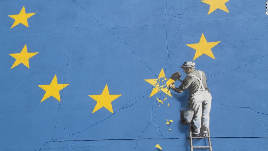 A person on a ladder chiseling away one of the stars in the EU banner