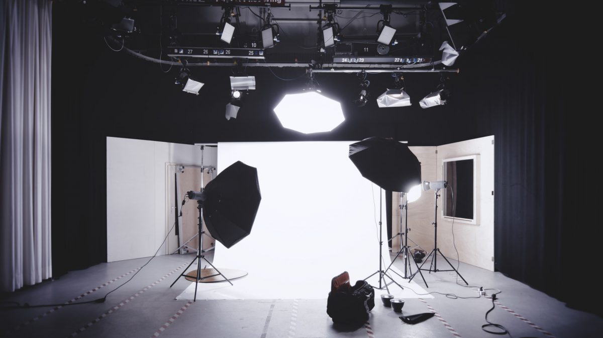 A photoshoot area with a white background sheet and a number of lights pointed at it