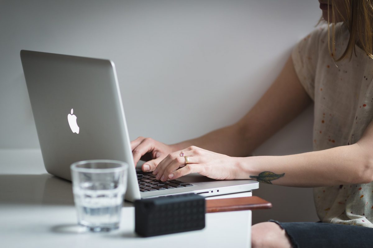 Person typing on a Macbook at their desk.