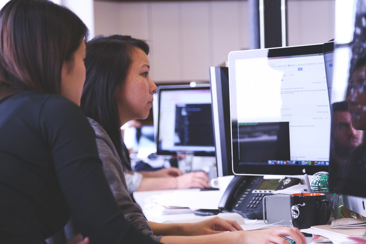 Two women working at desktop pcs