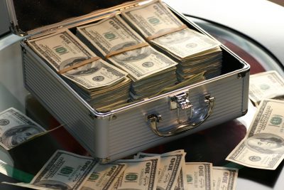 An opened briefcase on a table, full of dollar bills