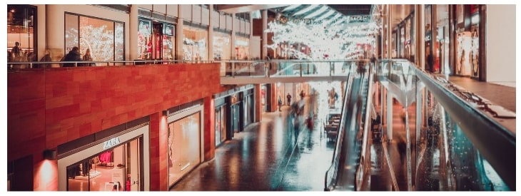 Inside a shopping center with people going up an escalator.