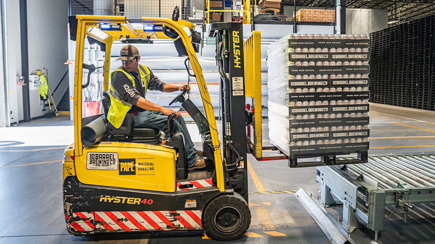 Warehouse worker moving pallets of stock through the warehouse.