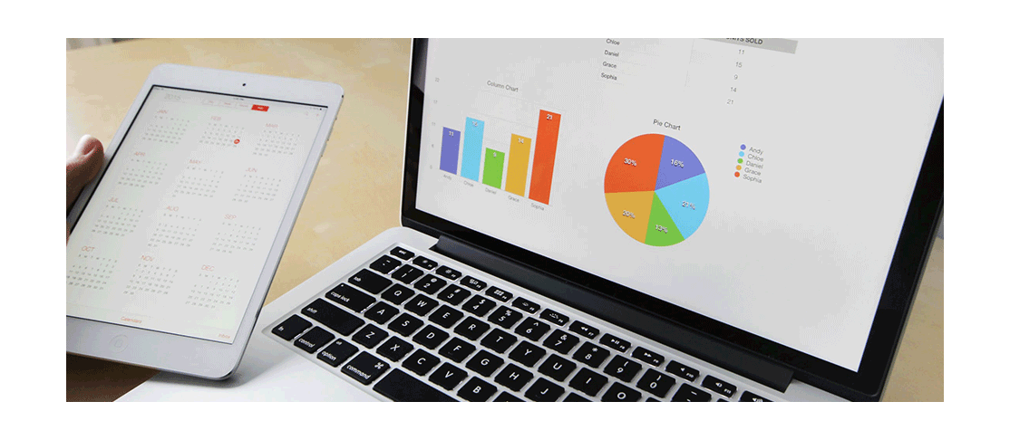 A laptop showing a number of graphs on the screen, with a tablet pc being held next to it showing calendars