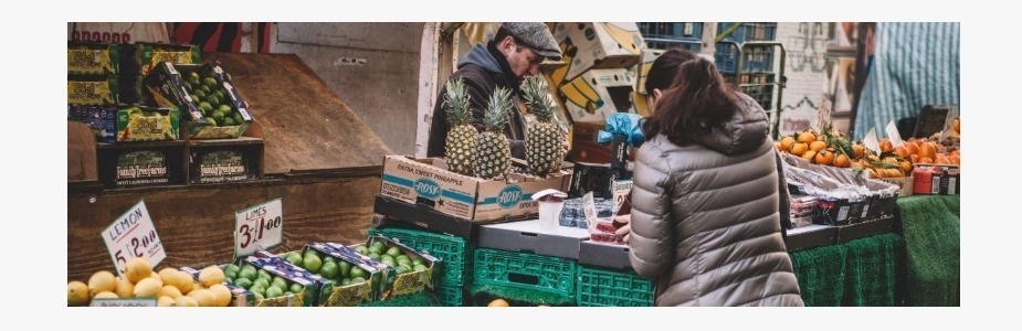 A woman looking at fruit on a stall in an outside market place