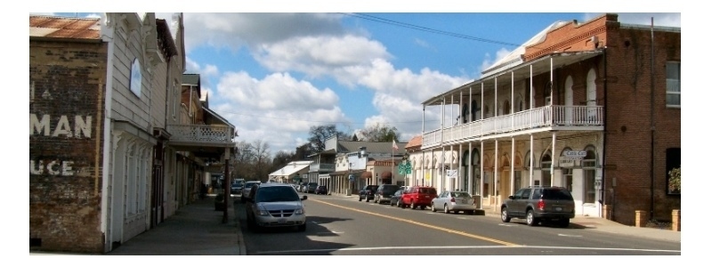 A road with cars parked on it, with buildings either side of it