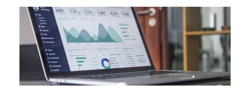 A laptop on a desk showing a range of charts with trends and sales figures