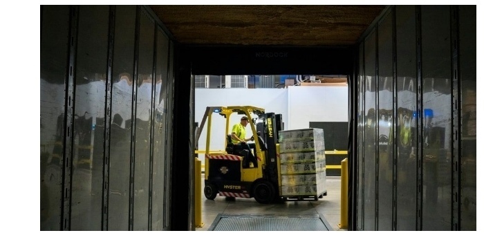 View through a shipping container of a person using a forklift