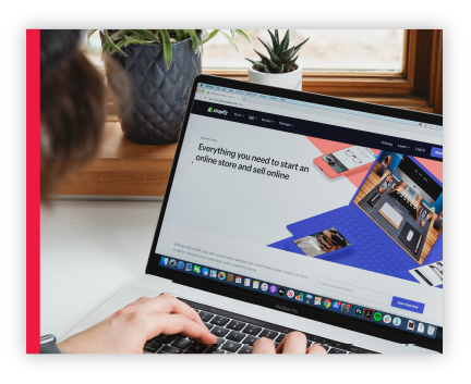 Person surfing the Shopify homepage on their laptop.