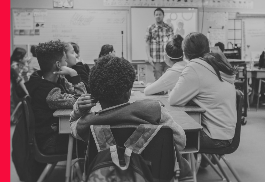 A teacher speaking to a group of children in a classroom