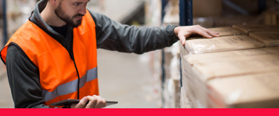 Person wearing a high vis in a warehouse looking at a box