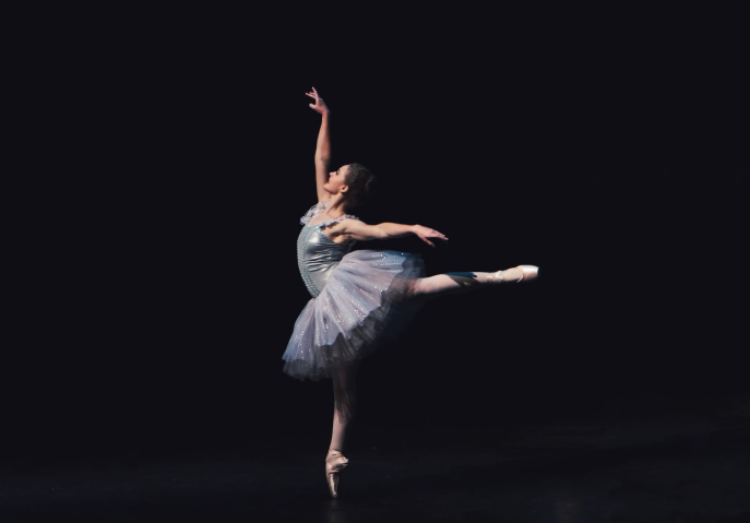 A ballet dancer pirouetting in front of a black background