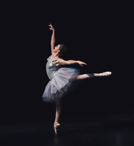 A ballet dancer pirouetting in front of a black background