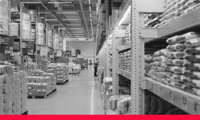 The view along the front of a section of racking in a store with a number of pallets of products next to it