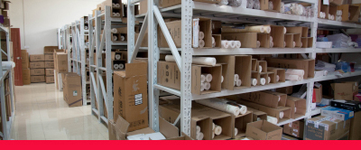 Four sections of racking with boxes of products on them, and stacked boxes in front of them on the floor