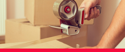 A hand holding a tape dispenser closing up the top of a box