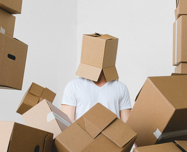 A person with a box on their head in a room surrounded by boxes