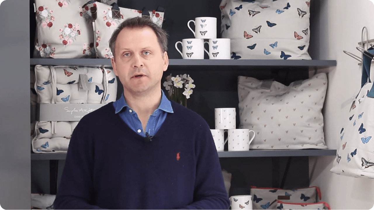 A man standing in front of shelves with mugs and cushions on them
