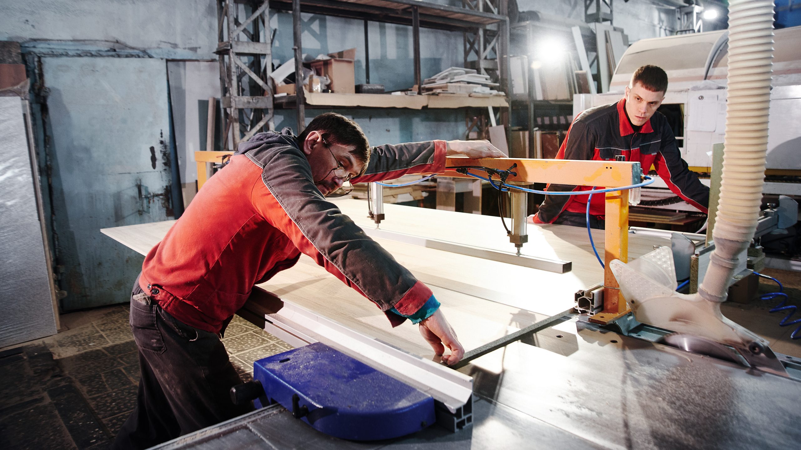 Process of production and manufacture of wooden furniture in furniture factory. Worker carpenter man in overalls processes wood on special equipment