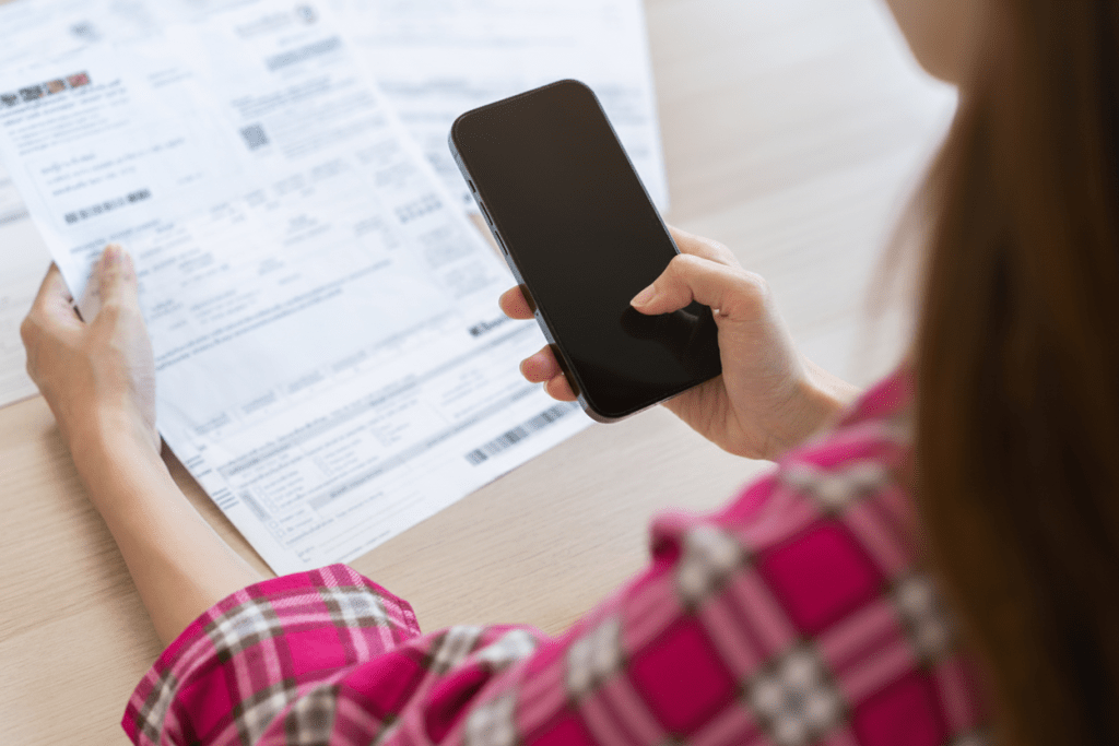 A woman sat at a desk looking over orders and her phone.
