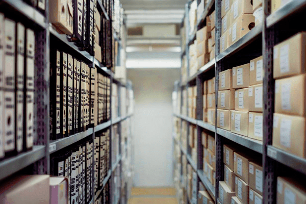 Boxes and files being stored along metal shelves.