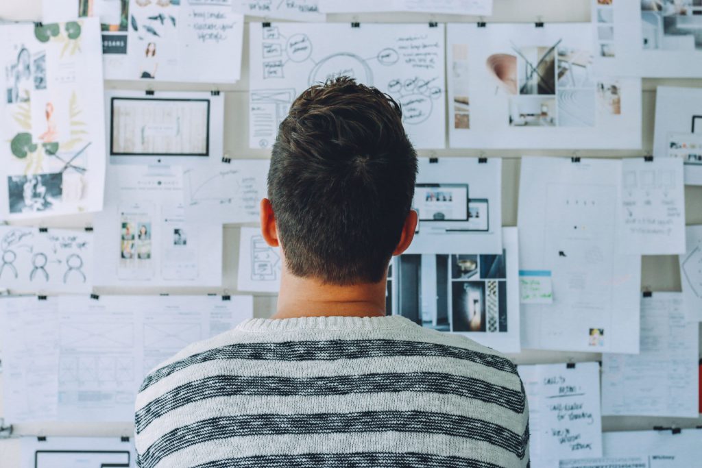 A man looking at a wall with a number of graphs pinned to it